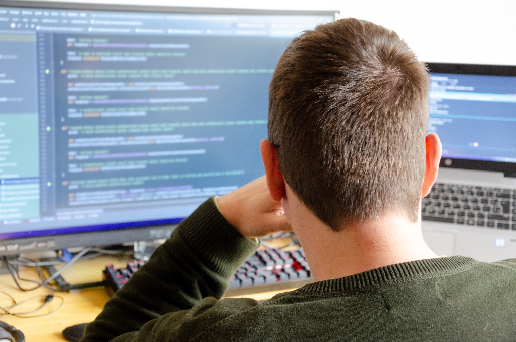 over shoulder view of man in green sweater looking at code